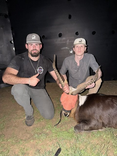 Two crew members with a Nile lechwe at night